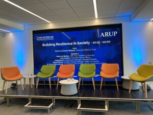 Empty chairs on a stage with a screen saying 'Building Resilience in Society'